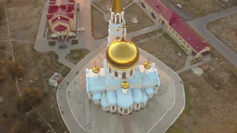 Aerial-wunderschöne-Gold-und-weiß-Kirche-während-des-Sonnenuntergangs-gegen-die-fantastische-Skyline