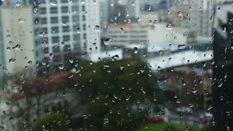 Rain-drops-falls-on-a-window-with-urban-cityscape-view