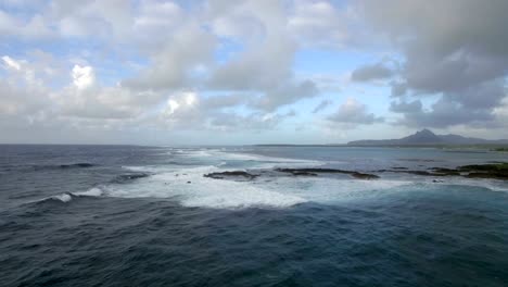 Aerial-view-of-water-line-of-seas-that-do-not-mix-against-blue-sky-with-clouds,-Mauritius-Island