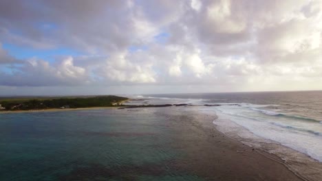 Aerial-view-of-water-line-of-seas-that-do-not-mix-against-blue-sky-with-clouds,-Mauritius-Island