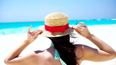 Rückansicht-der-schönen-Frau-im-Hut-auf-Sommerferien-am-weißen-Strand.