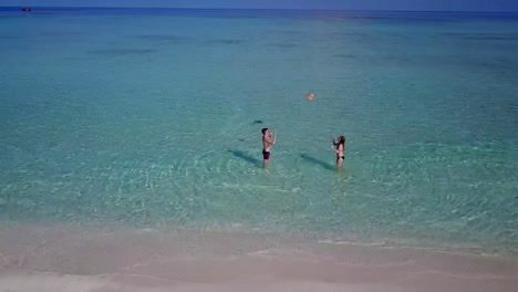 v03805-vista-aérea-de-drone-volador-de-playa-en-isla-paraíso-soleado-con-cielo-azul-aqua-mar-agua-océano-4k-2-personas-pareja-hombre-mujer-tocando-juntos-diversión-bola-blanco-Maldivas