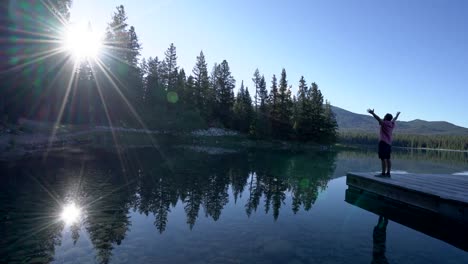 Man-arms-outreached-by-alpine-lake-in-the-Canadians-rockies