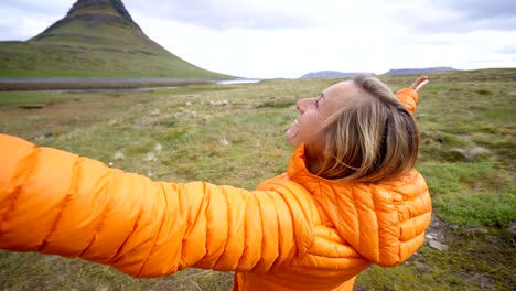 Young-woman-in-Iceland-arms-outstretched-for-freedom-Springtime-overcast-sky-at-famous-Kirkjufell-mountain