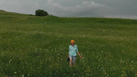 El-fotógrafo-de-la-chica-de-gafas-y-un-sombrero-camina-con-su-cámara-réflex-digital-en-el-borde-de-la-meseta-cerca-del-precipicio.-Vista-aérea