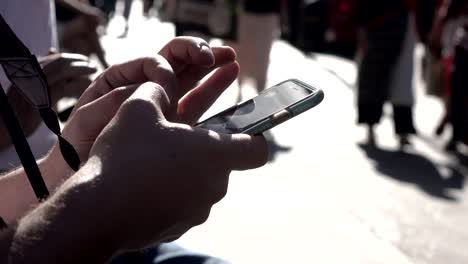 hands-of-tourists-typing-on-the-smartphone-in-a-crowded-street