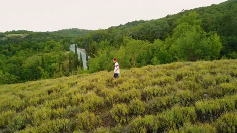 junger-Mann-lässig-zu-Fuß-auf-einem-Berg-Feld-am-Abend-während-der-Sommersaison