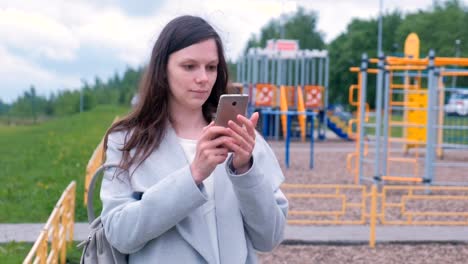 Young-woman-shoots-a-video-on-a-mobile-phone-on-the-Playground.