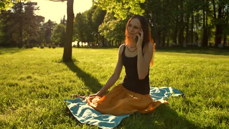 Mujer-sentada,-hablando-durante-una-llamada-de-teléfono-al-aire-libre-en-el-Parque