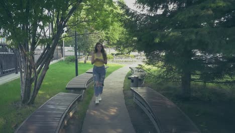 chica-caminando-en-el-parque-con-un-teléfono