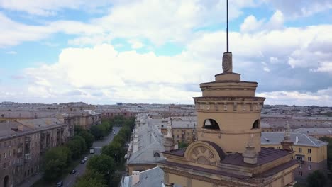 Drone-en-vuelo-cerca-de-la-torre-de-estilo-antiguo-con-fábrica-en-el-fondo