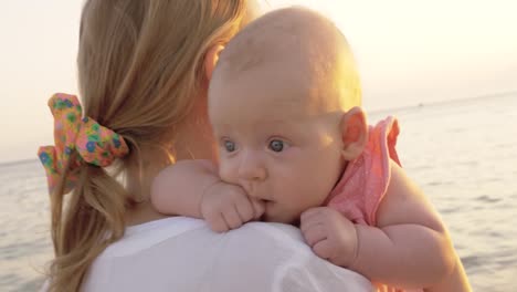 Mamá-con-hija-teniendo-a-pie-en-la-playa-al-atardecer