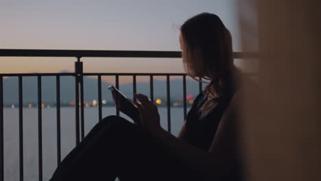 Frau-mit-Tablet-PC-auf-dem-Balkon-mit-Blick-auf-Meer