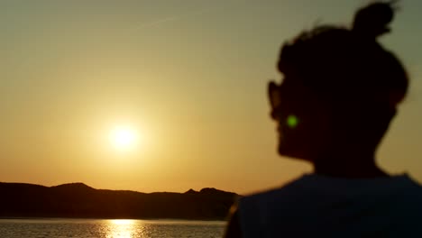 Silhouette-Of-Woman-Watching-Golden-Sunset-At-Beach