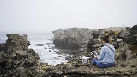 Mujer-anónima-con-drone-sentado-en-la-orilla-del-mar