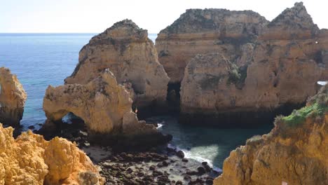 Ponta-da-Piedade,-lugar-famoso-en-el-sur-de-Portugal,-la-ciudad-de-lagos,-la-costa-rocosa,-olas-de-océano-Atlántico,-rocas-afiladas,-agua-azul,-flores-amarillas,-arco,-nadie,-playa-salvaje