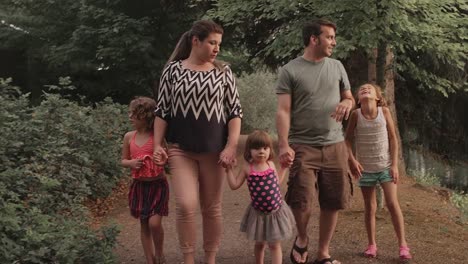 A-family-walking-down-a-park-trail-while-holding-hands