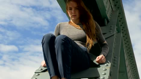 Young-Woman-Sitting-on-a-Bridge-Beam-Over-the-River-Main-2