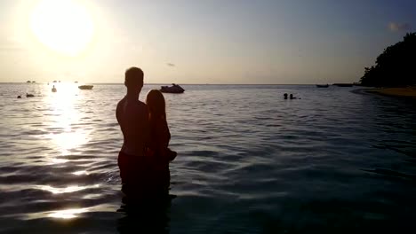 v04123-vuelo-drone-vista-aérea-de-Maldivas-playa-2-personas-pareja-hombre-mujer-amor-romántico-puesta-de-sol-salida-del-sol-en-la-isla-de-paraíso-tropical-soleado-con-cielo-azul-aqua-agua-mar-4k