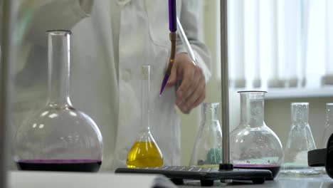Lab-technician-doing-experiment-in-lab.-Male-medical-or-scientific-laboratory-researcher-performs-tests-with-blue-liquid.-Scientist-working-with-flasks-in-laboratory