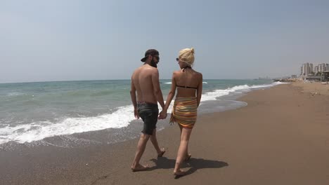 Young-couple-walking-together-on-a-beach.