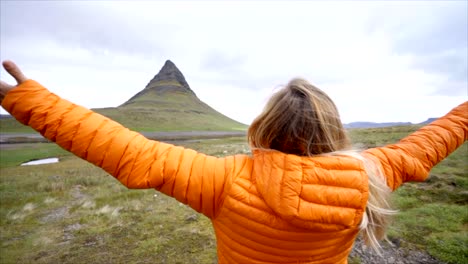 Young-woman-in-Iceland-arms-outstretched-for-freedom-Springtime-overcast-sky-at-famous-Kirkjufell-mountain