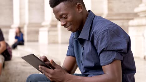 glücklich-entspannt-schwarzen-afrikanischen-Jüngling-mit-Tablet-sitzt-auf-der-Treppe