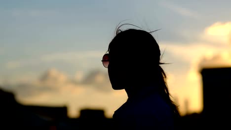 Hermosa-mujer-con-pelo-largo-rojo-en-la-azotea.-Puesta-de-sol-de-luz,-viento