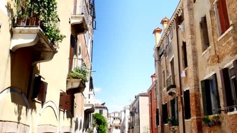 Venedig,-Italien---7.-Juli-2018:-schmalen-Kanal-zwischen-den-alten-Häusern-von-Venzia,-heißen-Sommertag