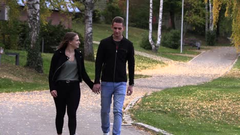 Young-guy-with-a-girl-walk-in-the-park,-holding-hands