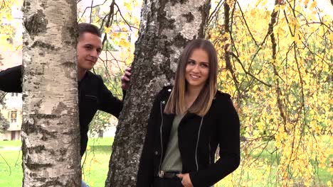 A-young-couple-sits-on-a-white-bedspread-in-autumn-park