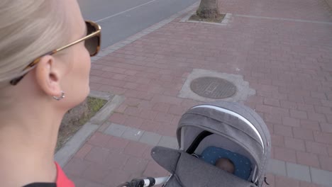 Young-mother-walking-with-baby-sleeping-in-pram