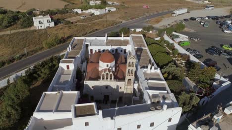 Aerial-view-of-Agios-Nikolaos-church-in-Spetses-next-to-a-road,-Greece.