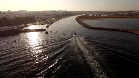 Boat-comes-into-the-harbor-at-sunset-aerial-view