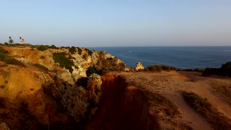 Ponta-da-Piedade-lighthouse-on-cliff-near-ocean-at-sunset,-Lagos,-aerial-view