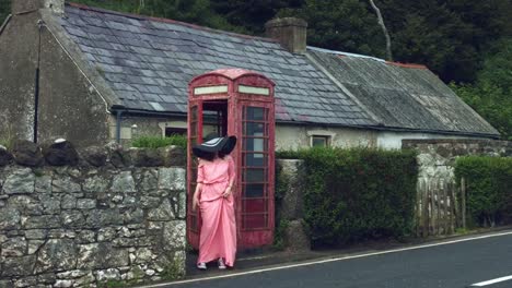 4k-Shot-of-a-Woman-posing-in-a-Red-Telephone-Box,-United-Kingdom