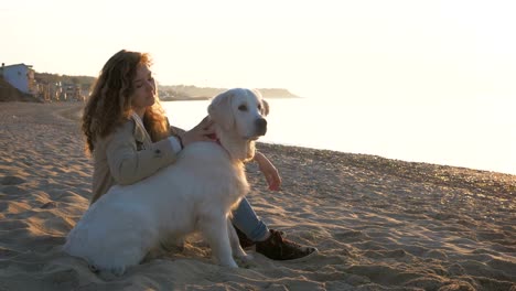 Junge-Frau-schnell-spielen-mit-Retriever-Hund-am-Strand-bei-Sonnenuntergang