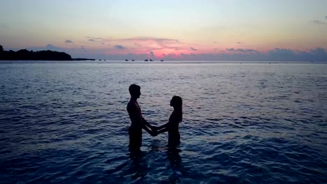 v04169-Aerial-flying-drone-view-of-Maldives-white-sandy-beach-2-people-young-couple-man-woman-romantic-love-sunset-sunrise-on-sunny-tropical-paradise-island-with-aqua-blue-sky-sea-water-ocean-4k