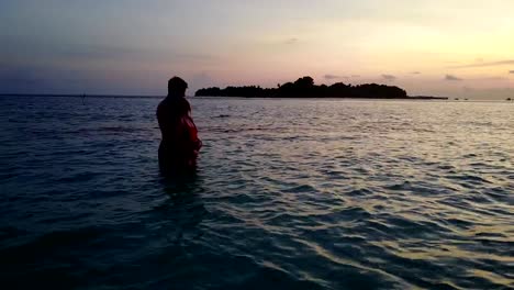 v04139-Aerial-flying-drone-view-of-Maldives-white-sandy-beach-2-people-young-couple-man-woman-romantic-love-sunset-sunrise-on-sunny-tropical-paradise-island-with-aqua-blue-sky-sea-water-ocean-4k