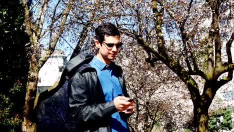 Man-using-mobile-phone-while-having-coffee-in-park-4k