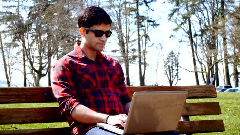 Man-using-laptop-in-the-park-4k