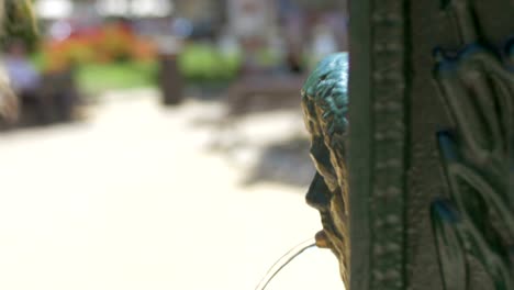 Blick-auf-junge,-blonde-Frau-in-schwarzer-Sonnenbrille-trinken-aus-alten-öffentlichen-Brunnen,-Valencia,-Spanien