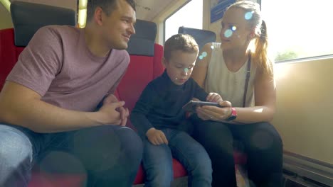 Family-with-child-traveling-by-train-and-using-cell