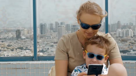 Mother-and-kid-on-hotel-rooftop-taking-selfie-with-cell.-Tel-Aviv,-Israel