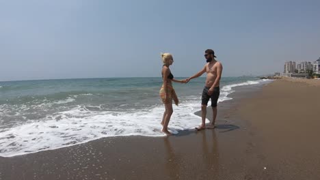 Young-couple-walking-together-on-a-beach.