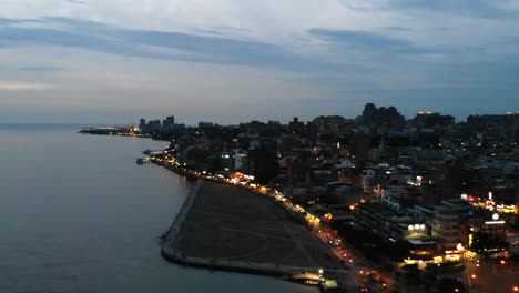 Rechts-Antenne-Pfanne-aus-Fluss,-Stadt-in-der-Abenddämmerung