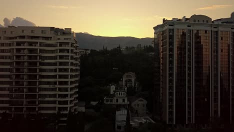 Silhouette-des-hohen-Wolkenkratzer-Gebäude-Wohnungen-leben,-rechtzeitig-ein-Sonnenuntergang-in-der-Nähe-der-Berge-und-Wolken