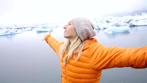 Young-woman-arms-outstretched-at-glacier-lagoon-in-Iceland-enjoying-freedom-in-nature-embracing-life-and-vitality
