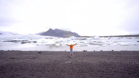 Brazos-de-la-joven-extendidos-en-la-laguna-de-glaciar-en-Islandia