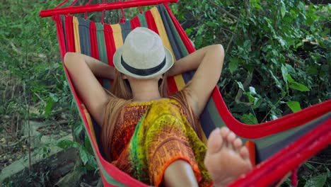 Mujer-joven-durmiendo-en-hamaca-con-sombrero-que-cubre-la-cara